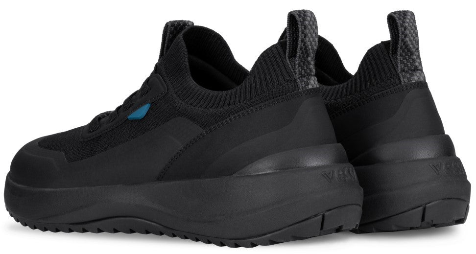 A pair of black athletic shoes shown from the rear three-quarter view, featuring a knit upper, a thick black midsole, a patterned pull tab at the heel, and a subtle blue accent on the side.