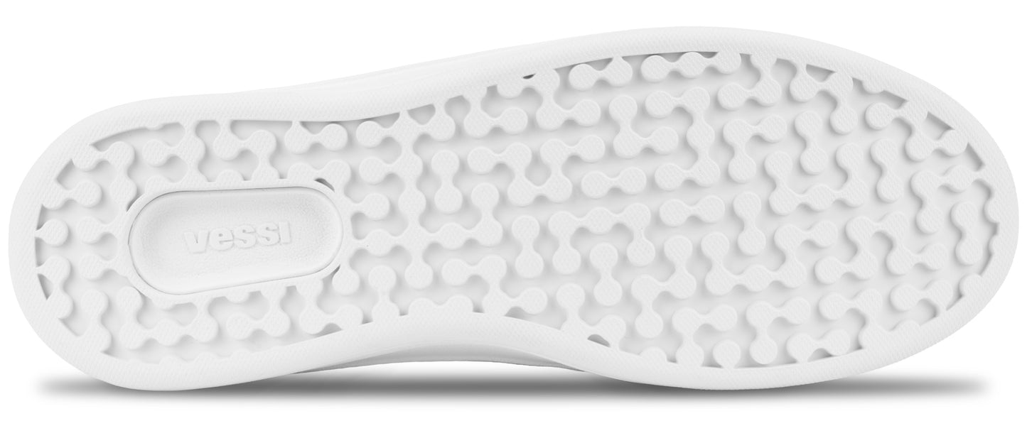 A view of the underside of a white sneaker sole featuring a pattern of small, rounded, interlocking shapes and the word Vessi embossed in a rectangular section.
