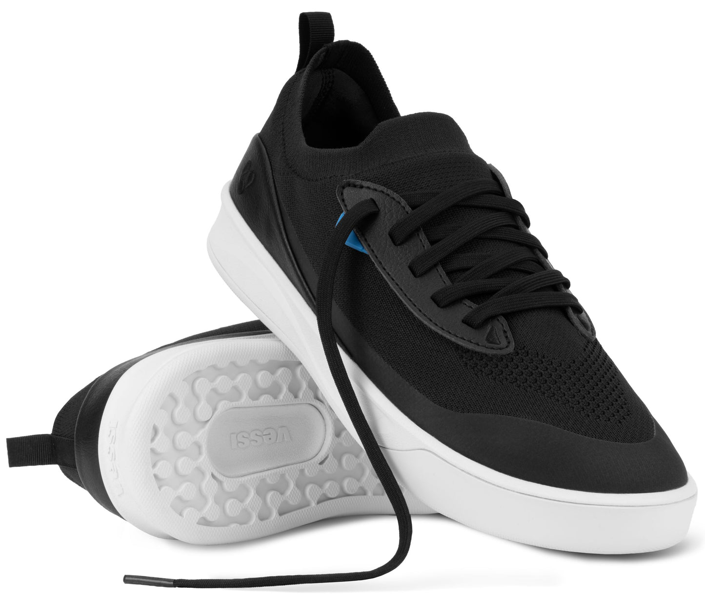 A pair of black and white athletic sneakers, with one shoe upright and the other lying on its side showing the patterned white rubber outsole with the word 'leessi' embossed in the center.
