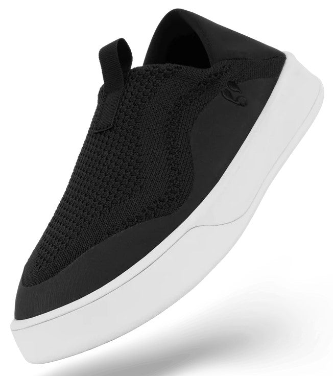 A slip-on sneaker featuring a black knit upper with a black reinforced toe cap and a white rubber sole.