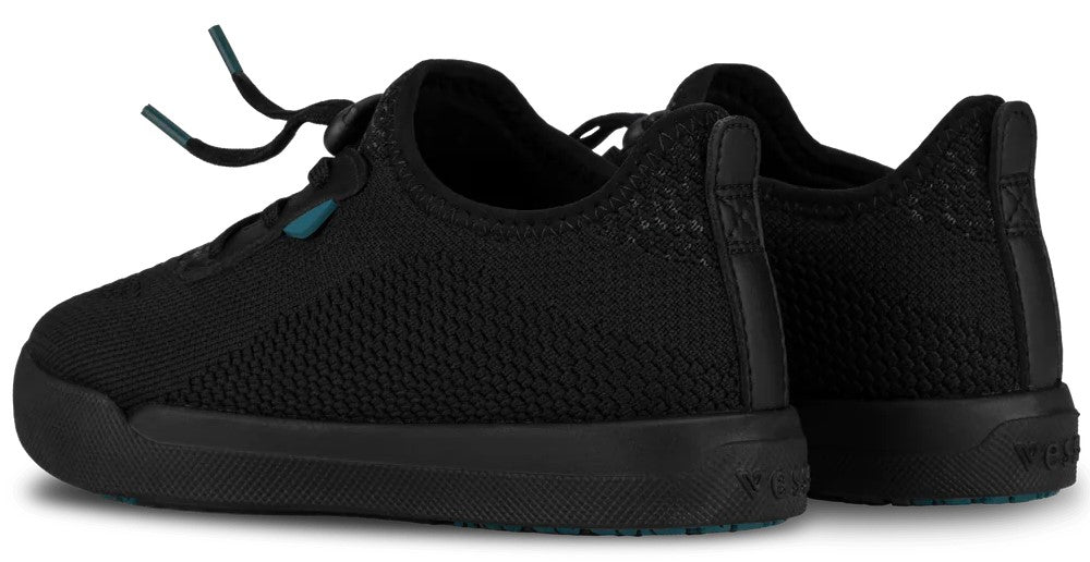 A pair of black, knitted, low-top slip-on sneakers with elastic laces and a textured black rubber sole, viewed from the side-rear angle.
