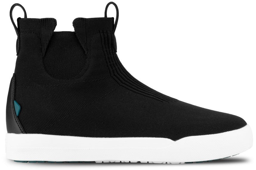 A black ankle-height slip-on sneaker with a knit fabric upper, dual pull tabs at the collar, a thick white rubber midsole, and a small teal accent tag on the heel.