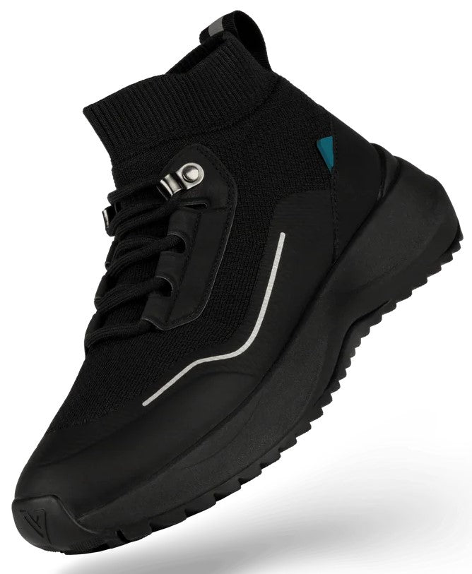A black mid-top sneaker with a knit upper, lace-up closure with metal eyelets, a thin reflective silver stripe on the side, a small teal accent near the ankle, and a chunky black treaded rubber sole.