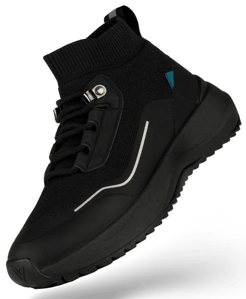 A black mid-top sneaker with a knit upper, lace-up closure with metal eyelets, a thin reflective silver stripe on the side, a small teal accent near the ankle, and a chunky black treaded rubber sole.