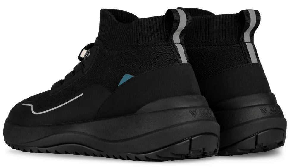 A pair of black, mid-top athletic sneakers with a knit upper, a thick black midsole, and a pull tab with a reflective silver stripe on the heel. A small teal accent is visible on the side of one shoe.