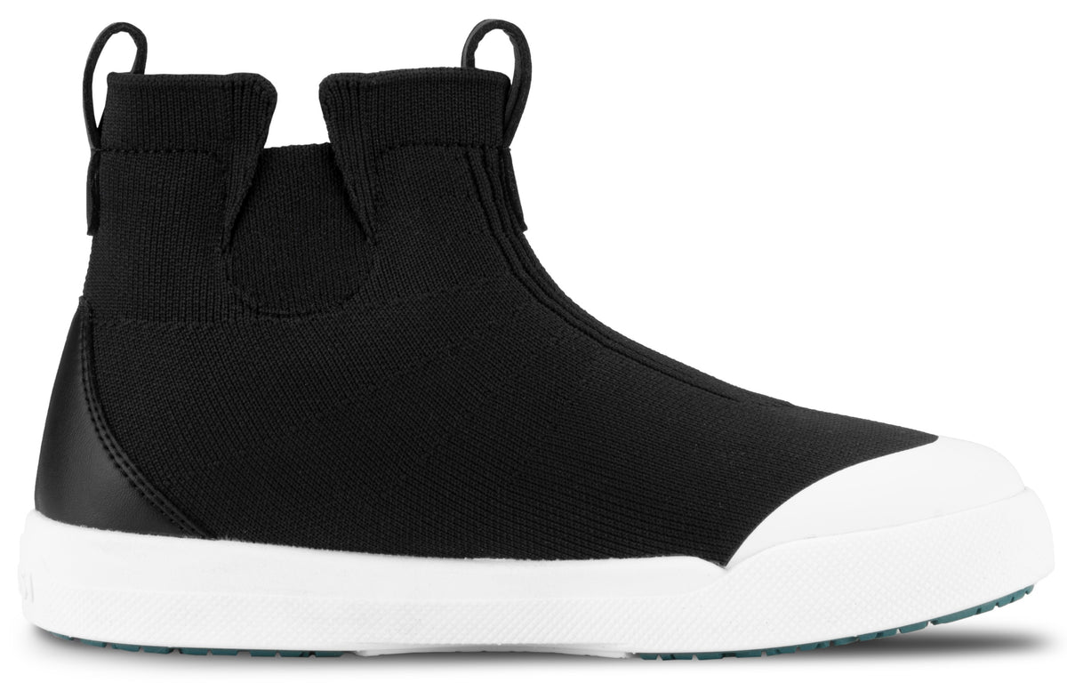 A black slip-on ankle boot with a white rubber toe cap and thick white rubber sole, featuring two pull tabs on the top collar.