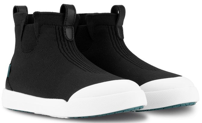 A pair of black ankle-high, slip-on shoes with a white, textured rubber toe cap and thick, flat white rubber sole.