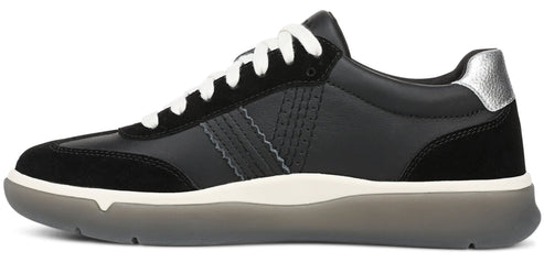 A black leather sneaker with black suede overlays at the toe and heel, white laces, a silver metallic detail on the heel tab, a thick off-white midsole, and a translucent grey rubber outsole.