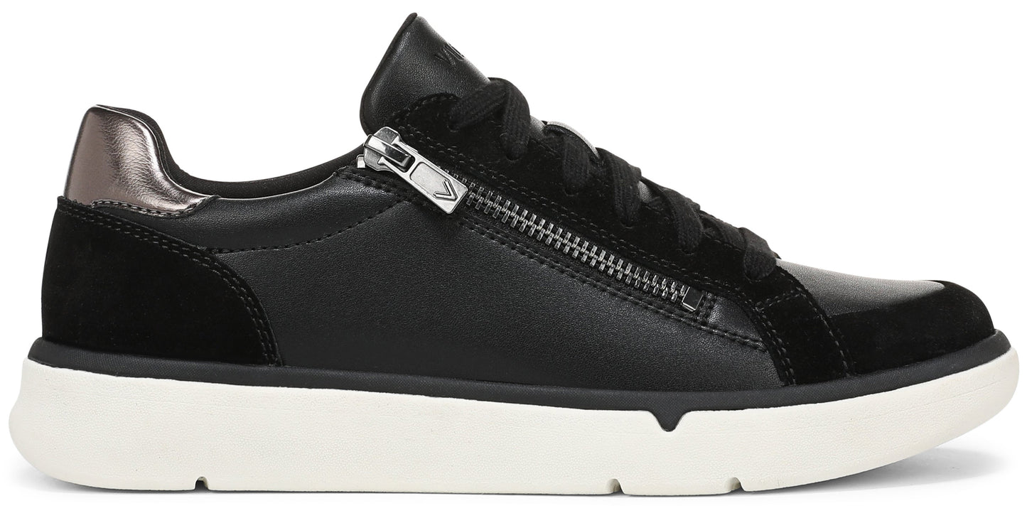 A black leather and suede casual sneaker with a white rubber sole, black laces, and a prominent silver zipper detail on the side near the collar, featuring a metallic bronze-toned heel patch.
