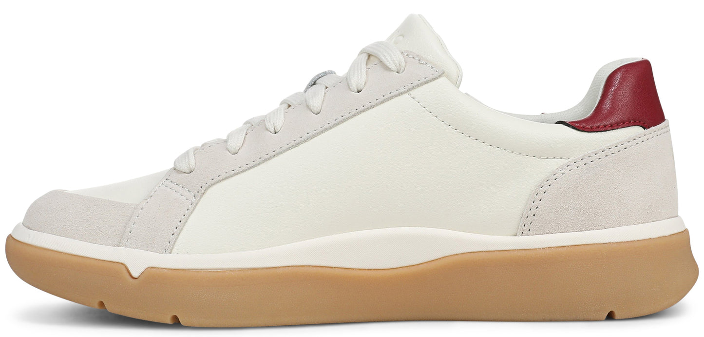 A low-top sneaker featuring a white upper with light gray suede overlays on the toe and lace eyelets, a tan rubber gum sole, and a deep red accent on the heel collar.