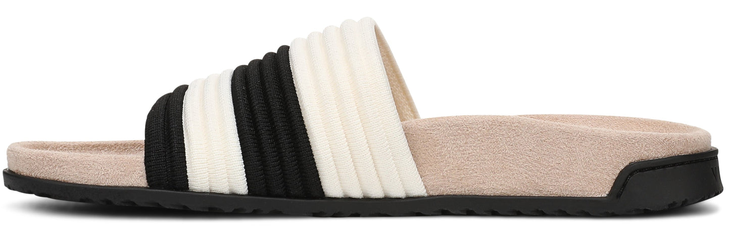 A slide sandal with black and white fabric over the foot, on a tan sole with a black bottom.