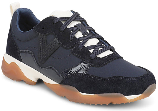 A low-top sneaker featuring navy blue suede and synthetic upper panels, a white tongue with dark blue laces, a V-shaped logo on the side, and a thick white midsole with a textured gum-rubber outsole.