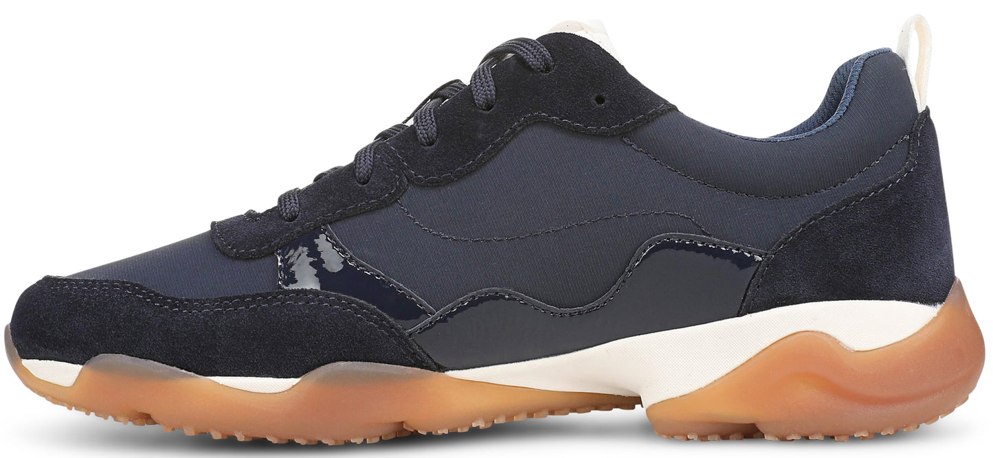 A low-top sneaker in dark blue with suede and synthetic panels, featuring a thick, white midsole and a translucent, wavy gum rubber outsole.