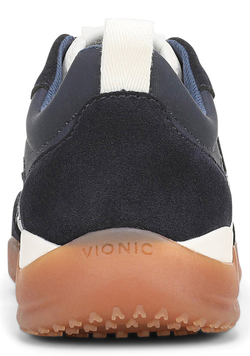 A close-up view of the heel of a dark navy blue sneaker, featuring a suede and smooth leather upper, a white midsole, and a gum-colored rubber outsole with the word VIONIC embossed on the back.