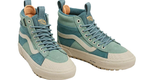 A pair of high-top sneakers, one facing left and one facing right, featuring teal suede and canvas with a cream wave on the sides, cream toe caps, and teal laces.