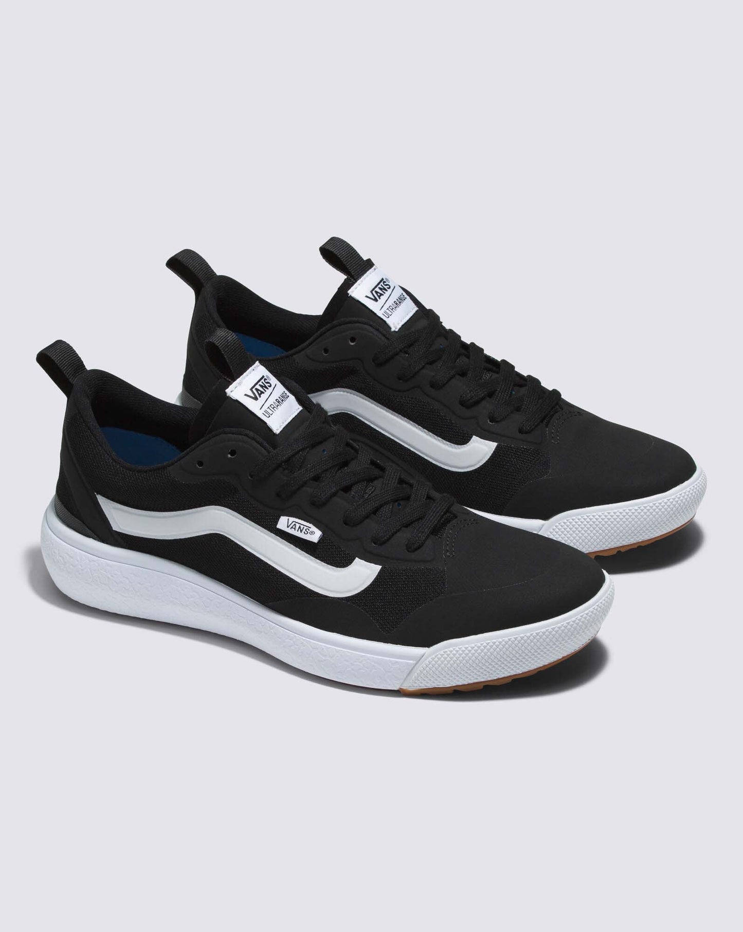 Two black sneakers with white curved stripes on a thick white sole, featuring a tongue label with white text.