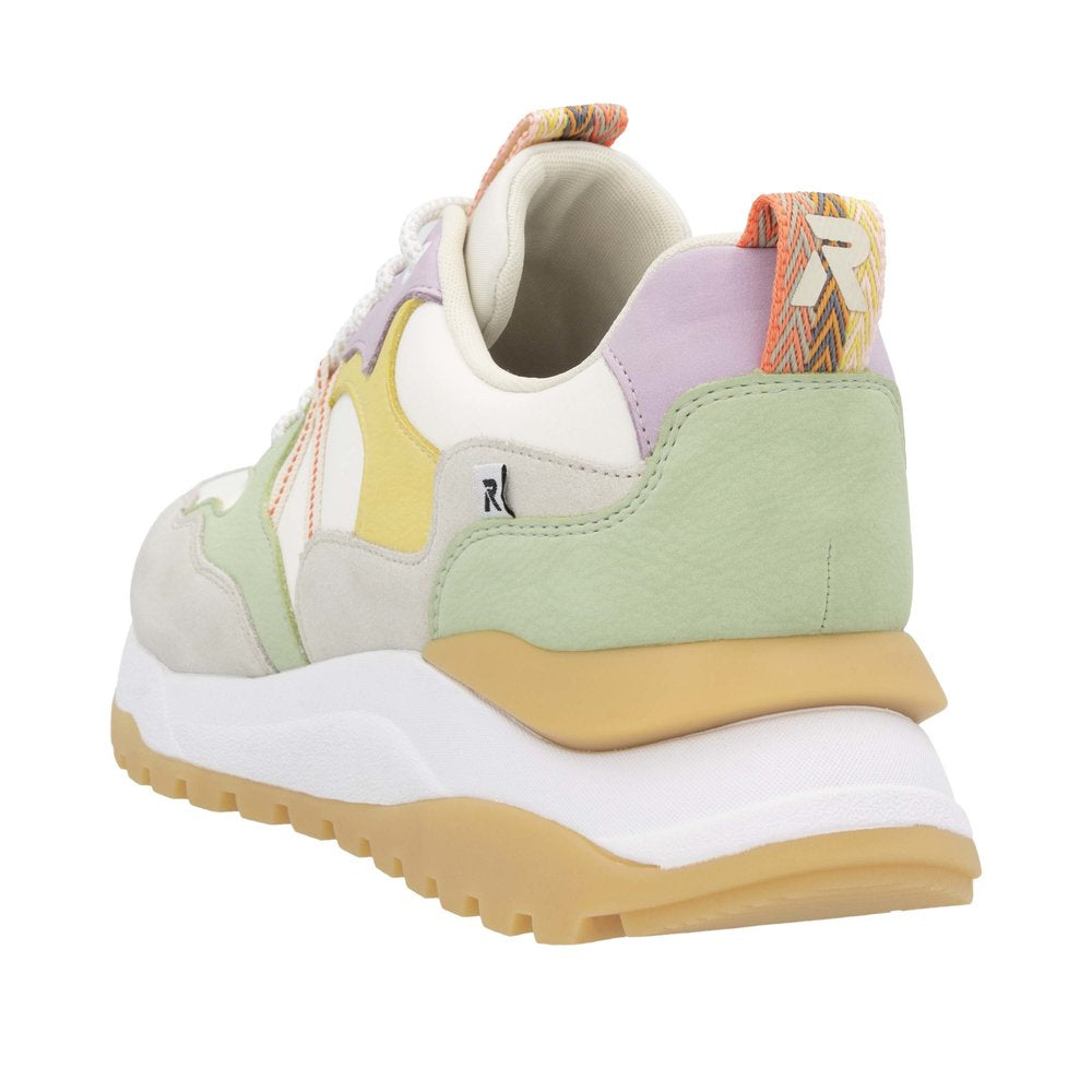 Low profile sneaker with a cream, yellow, light green and lavender patchwork upper, decorative white laces, and a thick white and tan sole.