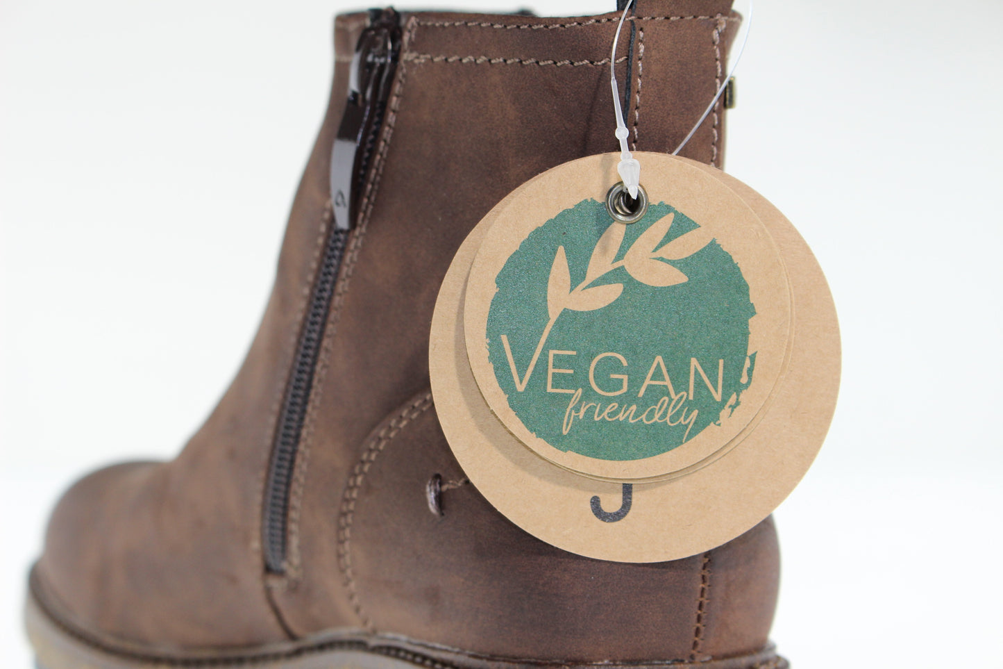 Close-up of brown ankle boot with side zipper and round "Vegan friendly" tag.