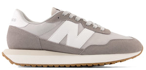A grey and white New Balance sneaker with a gum sole.