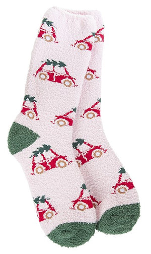 Pair of light pink fuzzy socks with a pattern of red cars carrying Christmas trees; the socks have green toes and heels.