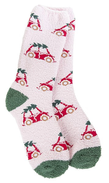 Pair of light pink fuzzy socks with a pattern of red cars carrying Christmas trees; the socks have green toes and heels.