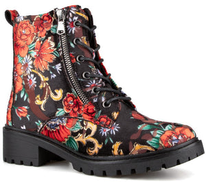A black ankle boot with a vibrant floral pattern in shades of red, orange, yellow, and green, featuring black laces, a side zipper, and a thick, lugged black rubber sole.