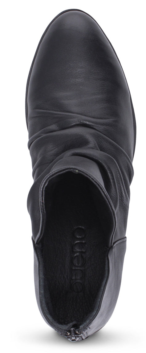 A top-down view of a black leather ankle boot with a round toe and a gathered vamp.