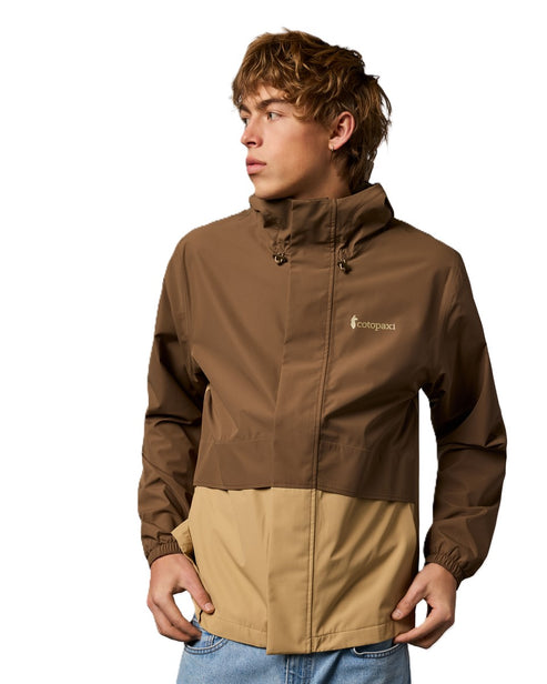 A man models a color-blocked brown and beige jacket with a small embroidered emblem.