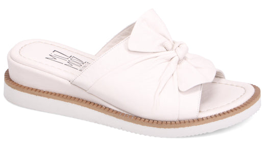White slide sandal with bow and a thin, tan midsole.