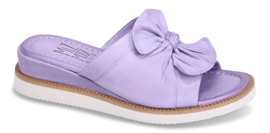 A purple leather sandal with a bow on top of the foot, and a white sole.