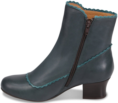 A teal leather ankle boot with a rounded toe, a low stacked heel, a side zipper, and decorative scalloped edges in a contrasting blue.
