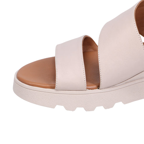 Close-up of a beige sandal with a tan footbed and thick white sole.