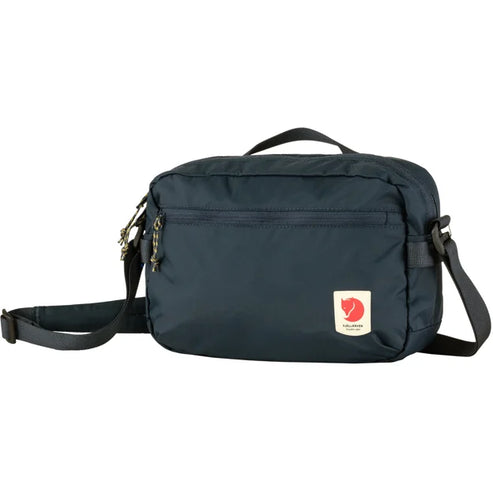 A dark blue messenger bag with a red and white circular logo attached.
