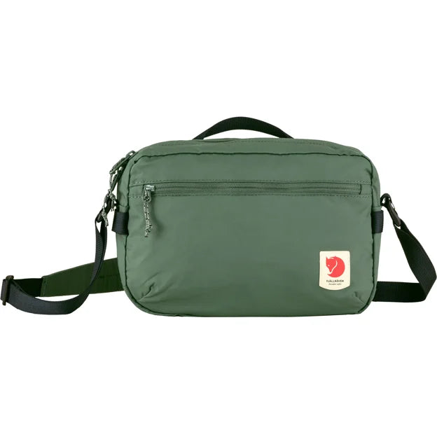 Green shoulder bag with a front zipper pocket and a red and white logo patch.