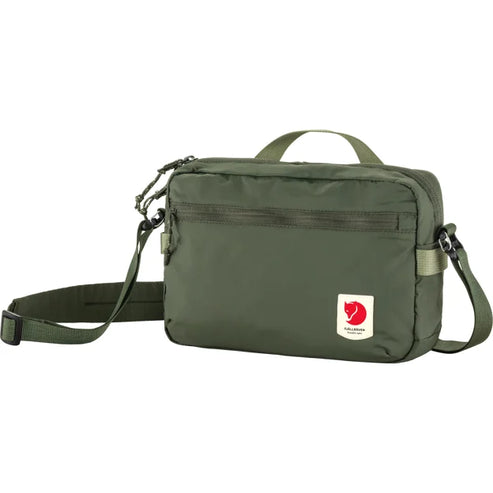 Olive-green crossbody bag with adjustable shoulder strap, top handle, zippered top closure, front zippered pocket, and red logo.