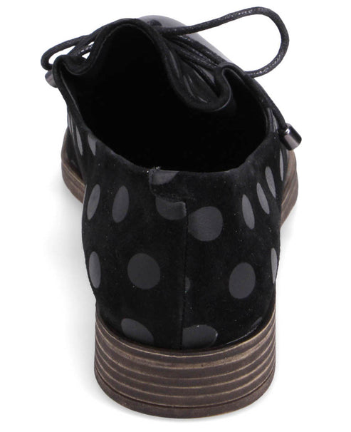 Back of a black suede oxford shoe with large black polka dots, featuring a lace-up closure and a low stacked heel.