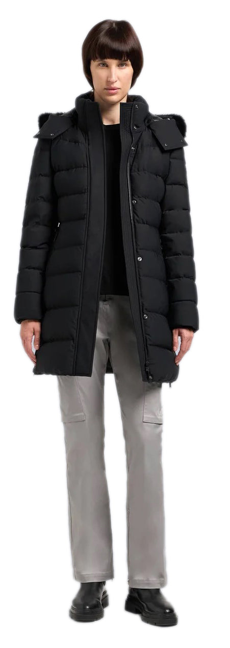 A woman wearing a black puffer coat, gray pants, and black shoes.