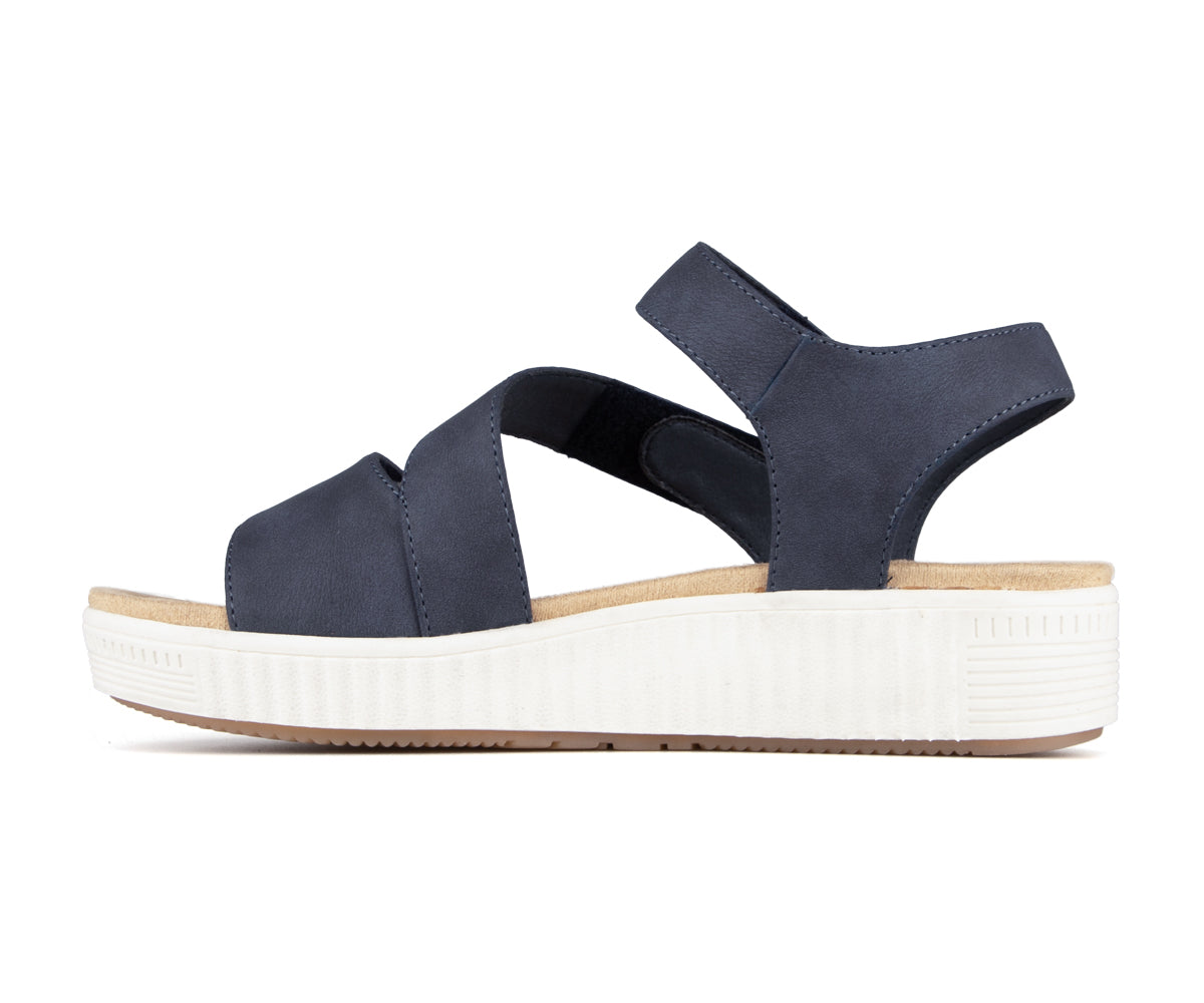Side view of a navy blue sandal with crossover straps and a white platform sole.