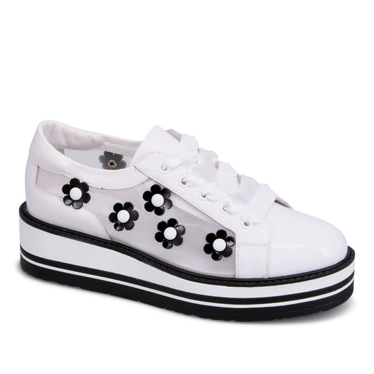 White platform sneaker with sheer side panels adorned with black flower appliques and white laces.