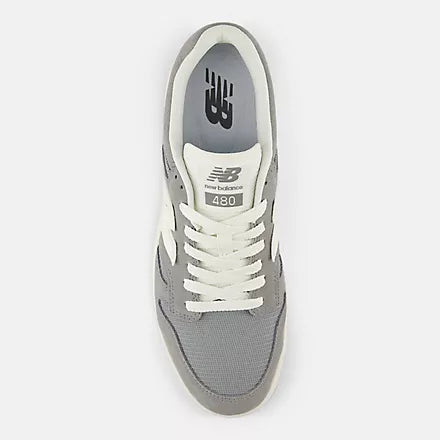 Top-down view of gray and white sneaker with NB logo on the tongue and inside heel.