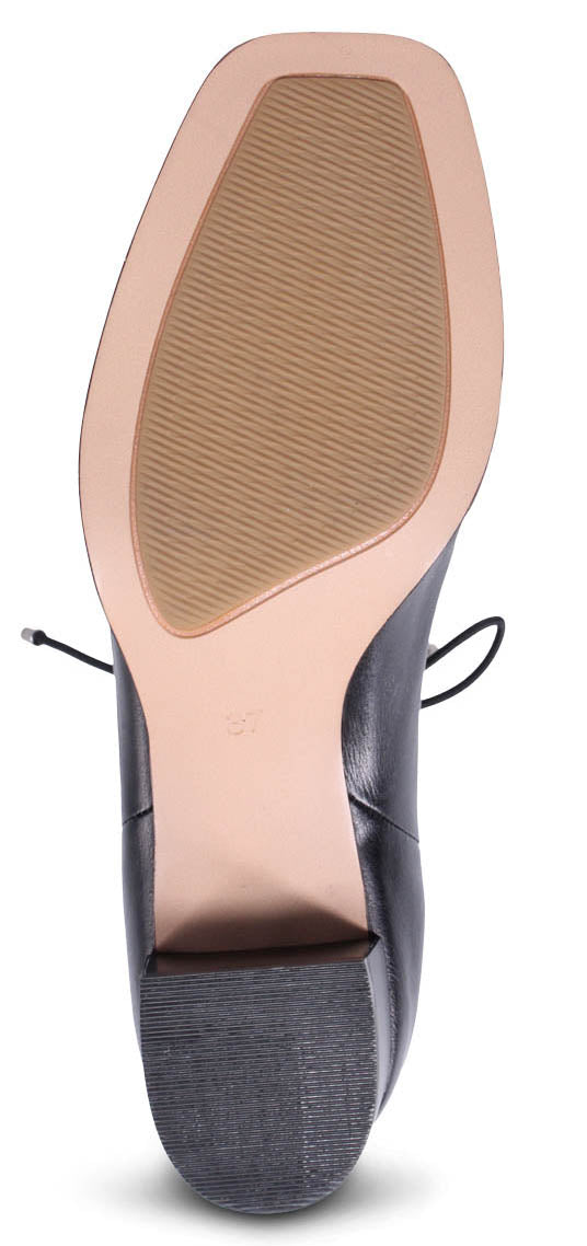 Bottom view of a black dress shoe with a textured tan sole.