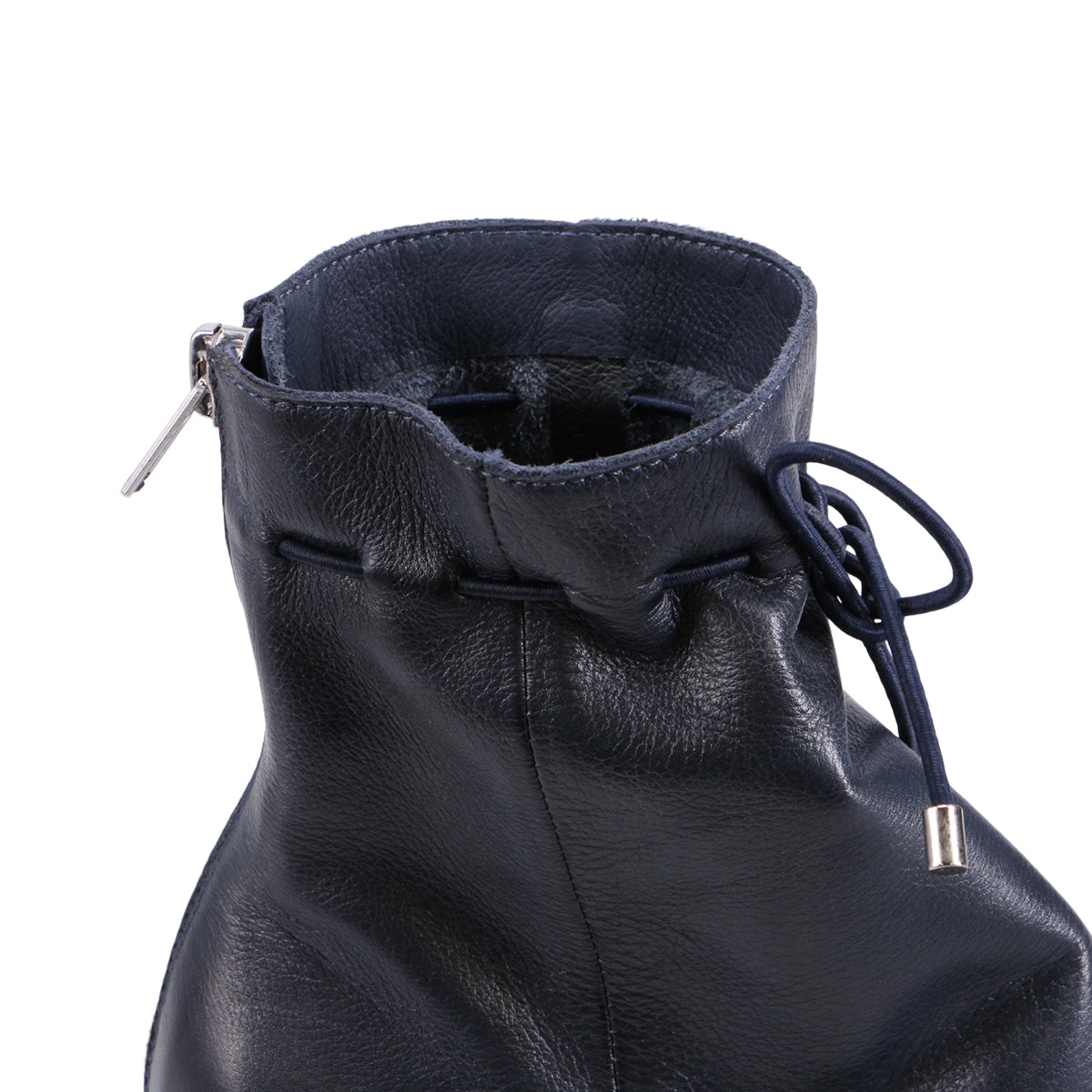 Close up of the top of a navy blue, leather ankle boot with a silver zipper.