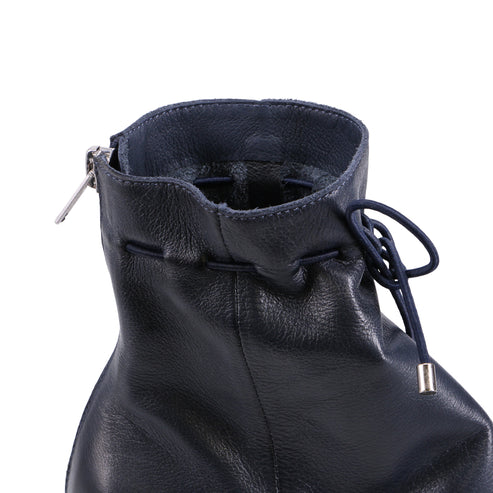 Close up of the top of a navy blue, leather ankle boot with a silver zipper.
