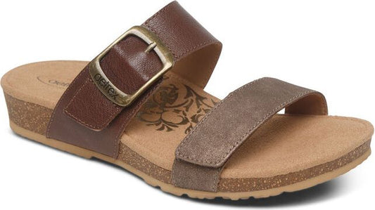Brown sandal with a thick strap featuring a large buckle and a second thin velcro strap.