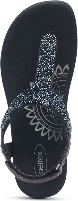 A top-down view of a black flip-flop sandal with a strap covered in silver sparkles and a mandala design on the footbed.