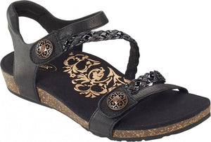 Black sandal with braided strap and decorative buttons.