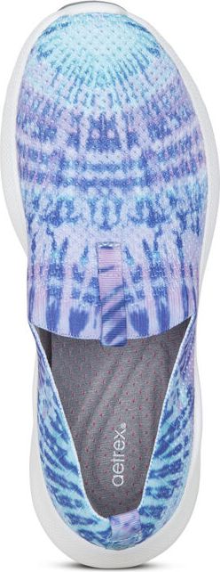 A top-down view of a blue and purple tie-dye slip-on shoe with a white sole. The insole is gray and has the text "aetrex."