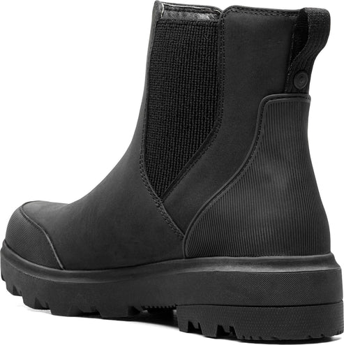 Close-up of a black boot with elastic side and thick treaded sole.