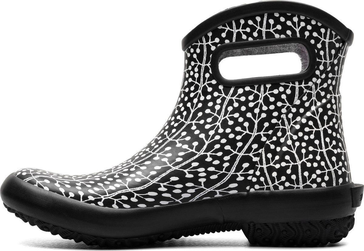 Short black rain boot with white botanical pattern, black sole and handle.