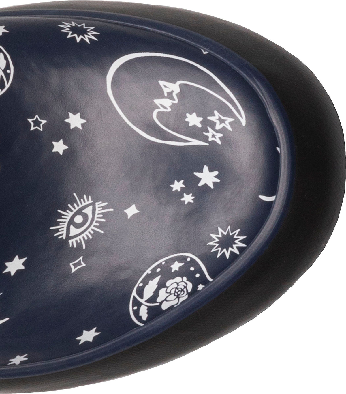 Close-up of a dark blue shoe sole with white celestial print, including moons, stars, eyes, and roses.